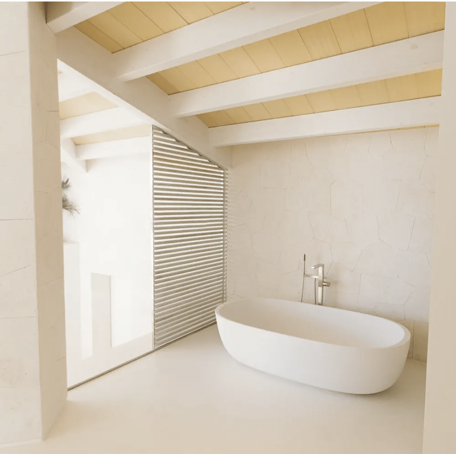 Bright bathroom with a seamless microcement floor and a freestanding tub, finished by Eco Lux Concepts